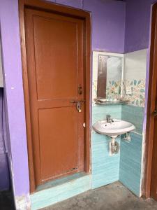 a bathroom with a sink and a wooden door at The Kapil Homestay in Manamaiju