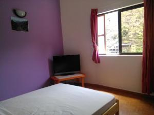 a bedroom with a bed and a tv and a window at Damontanha in Ribeira Grande