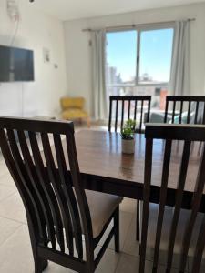 a dining room table with three chairs and a table and a table at Belgrano Apart in Comodoro Rivadavia