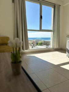a living room with a large window and a vase of flowers at Belgrano Apart in Comodoro Rivadavia