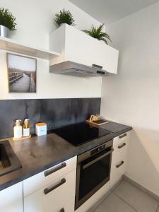 a kitchen with white cabinets and a black counter top at T2 avec Terrasse & Garage Privé - 53m2 - Proche Jaude in Chamalières +12 photos