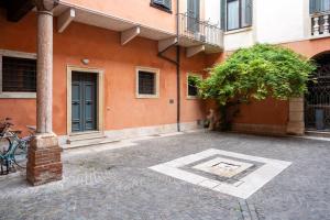 维罗纳SWEETHOME DOMUS 250mq nel centro di Verona con vista sul Teatro Romano的庭院里有一栋建筑，建筑上有一根柱子和一棵树。