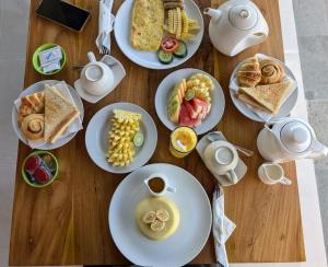 a wooden table topped with plates of breakfast foods at KAPI Sebatu Villa in Tampaksiring