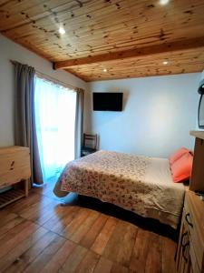 een slaapkamer met een bed en een televisie aan de muur bij La casita de Bonsai in Chapadmalal