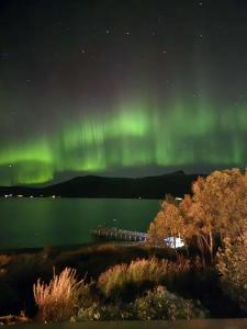 Eine Aurora über einem Wasserkörper in der Nacht in der Unterkunft Nordic Sauna Retreat in Tromsø