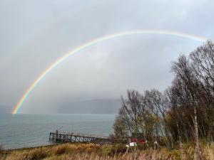ein Regenbogen über dem Wasser mit einem Pier in der Unterkunft Nordic Sauna Retreat in Tromsø