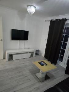 een woonkamer met een flatscreen-tv aan de muur bij Starfluence Properties - Spacious Ensuite in Gravesend