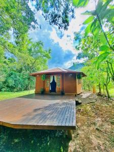 a small house with a wooden deck in a field at Cabana Betari - Petar in Iporanga