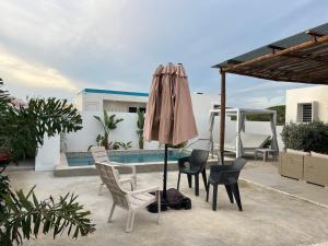 a patio with chairs and an umbrella next to a pool at Casa Wechi - Private Pool Central Gated Villa in Willemstad