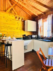 a kitchen with white cabinets and a wooden wall at Cabana Betari - Petar in Iporanga
