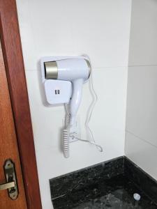 a white hair dryer on a wall in a bathroom at Ape 202 perto da UFV in Viçosa