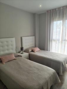 a bedroom with two beds and a window at Los Alamos Breeze - Modern Beach Apartment in Torremolinos +22 photos