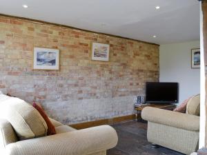 a living room with two chairs and a tv at The Cart Lodge-E3568 in Uggeshall