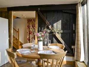 a dining room table with chairs and flowers on it at The Cart Lodge-E3568 in Uggeshall