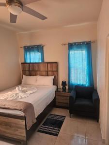 a bedroom with a bed and a chair and blue curtains at Suite Serene At Phoenix Park Village 1 in Portmore