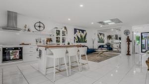 a white kitchen with a counter and some chairs at The Luxe Waterfront in Sandstone Point