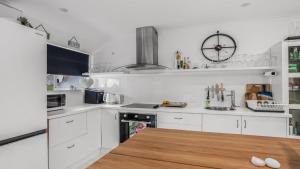 a kitchen with white cabinets and a clock on the wall at The Luxe Waterfront in Sandstone Point +15 photos