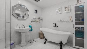 a white bathroom with a tub and a sink at The Luxe Waterfront in Sandstone Point
