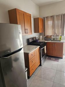 a kitchen with a stainless steel refrigerator and wooden cabinets at Suite Serene At Phoenix Park Village 1 in Portmore