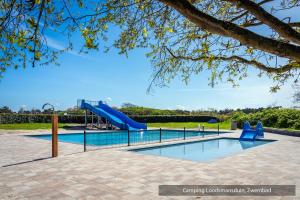 a swimming pool with a slide in a park at Camping Loodsmansduin in Den Hoorn