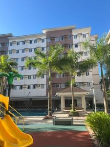 een groot gebouw met palmbomen en een speeltuin bij HOPE RESIDENCES UNIT 606 building D in Trece Martires