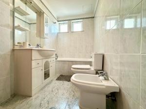 een witte badkamer met een wastafel en een toilet bij Lido Funchal in Funchal