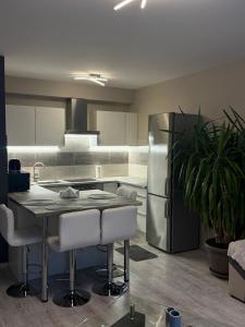 a kitchen with a table and a stainless steel refrigerator at HIGHWAY Apartman in Győr +5 photos