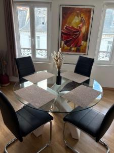 Un comedor con una mesa de cristal y sillas. en Le Cocon Chalonnais, en Châlons-en-Champagne
