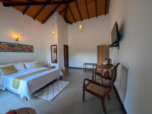 a bedroom with a bed and a tv and a chair at Windy Ridge Kandy in Kandy