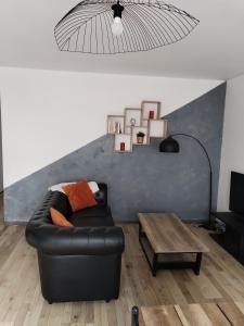 Una sala de estar con un sofá de cuero y una mesa. en Appartement Cosy, en Louhans 1 foto más