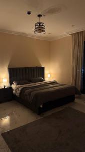 a bedroom with a large bed with two lamps at نسمة الخبر سويت in Dammam +5 photos
