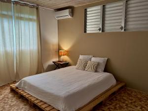 een slaapkamer met een bed met een spiegel en een raam bij Terrasse Panoramique, Calme et Spacieux, Vue sur Mer in Le Lamentin