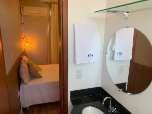 a bathroom with a sink and a mirror and a bed at Apê 301 a 2,8 km da UFV in Viçosa