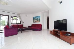 a living room with red furniture and a flat screen tv at Résidence Hôtelière TAZ in Kribi