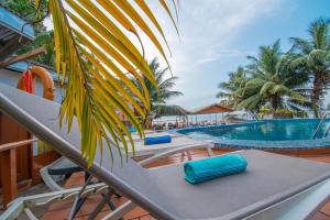 a pool with two lounge chairs and a palm tree at Résidence Hôtelière TAZ in Kribi