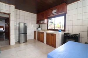a kitchen with wooden cabinets and a stainless steel refrigerator at Résidence Hôtelière TAZ in Kribi