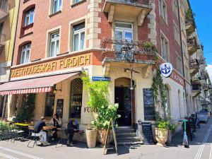 a building with people sitting at tables outside of it at Guesthouse fürDich in Zurich