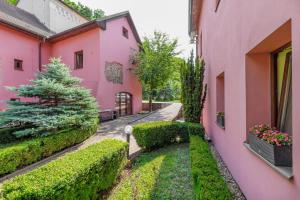 an alleyway between two pink buildings with bushes at Hotel STARÝ PIVOVAR in Prague