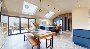 Una cocina con gabinetes azules y una mesa de madera. en The Bungalow by The Garden Spa Stays, 4 bed, Sauna - Hot Tub - Ice Bath, en Radstock