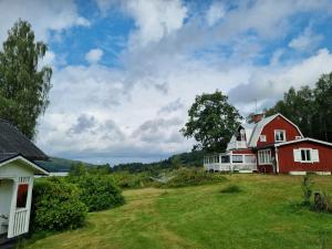 un granero rojo y una casa blanca en un campo en Idyllic Lake House in Sweden, en Klässbol