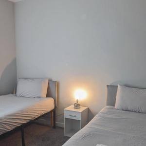 twee bedden in een kamer met een lamp op een nachtkastje bij Pitchside House - sleeps 4 in Liverpool +16 foto's