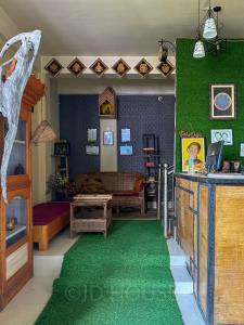 a living room with a green carpet and a bedroom at JD House in Tawang