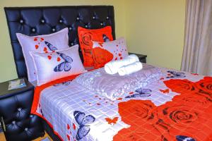 a bed with an orange and blue comforter and pillows at E Point guest house in Johannesburg +1 photo
