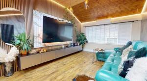 sala de estar con sofá azul y TV de pantalla grande en The Bungalow by The Garden Spa Stays, 4 bed, Sauna - Hot Tub - Ice Bath, en Radstock