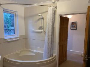 a bathroom with a tub and a shower with a window at Grace Cottage-a 4 bedroom period cottage in Teignmouth