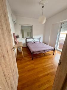een slaapkamer met een bed en een houten vloer bij 55sm apartment Voula 4pax in Athene