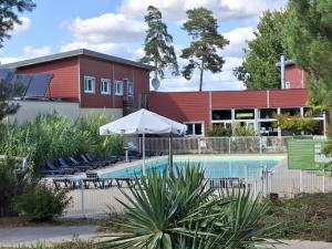 a pool with chairs and an umbrella in front of a building at Cottage Rembrandt in Chaveignes