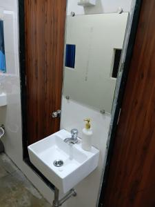 a bathroom with a white sink and a mirror at Hans Dormitory in Mumbai +18 photos