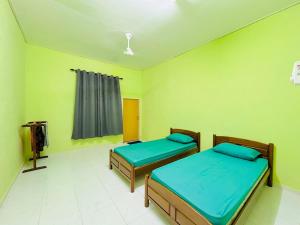 two beds in a room with green walls at Z Homestay in Kuala Terengganu