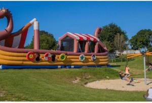 Un enfant joue dans une aire de jeux avec un dinosaure gonflable dans l'établissement DOMA Mobil home 3 chambres Litteau, à Litteau